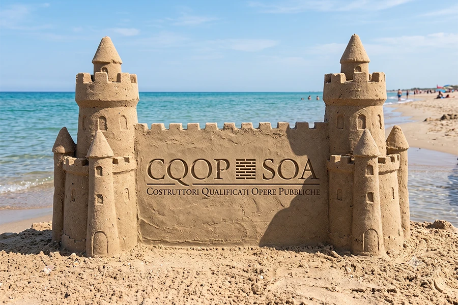 Castello di sabbia in spiaggia con logo CQOP